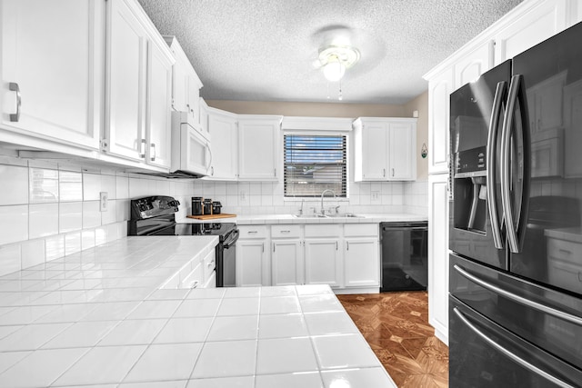 kitchen with tasteful backsplash, black appliances, tile countertops, white cabinetry, and a sink