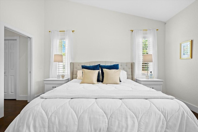 bedroom with lofted ceiling, dark wood-style floors, and baseboards