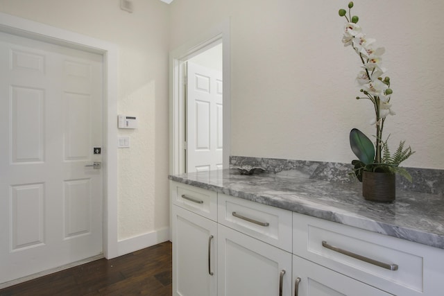 bathroom with a textured wall, wood finished floors, vanity, and baseboards