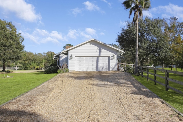 exterior space featuring gravel driveway, fence, an attached garage, and a lawn