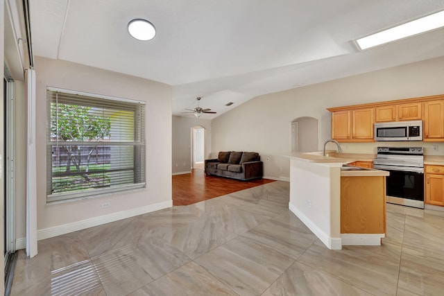 kitchen with sink, ceiling fan, stainless steel appliances, vaulted ceiling, and light brown cabinets