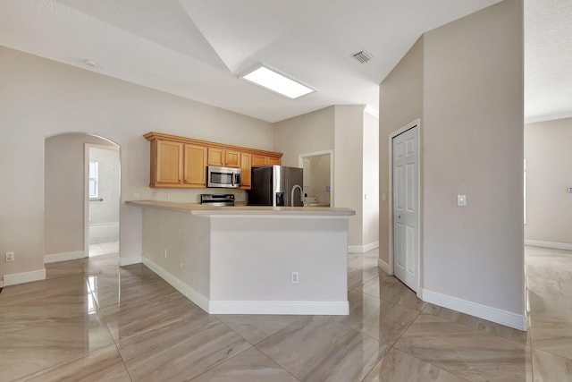 kitchen featuring lofted ceiling, stainless steel appliances, and kitchen peninsula