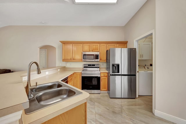 kitchen featuring sink, stainless steel appliances, washer and dryer, vaulted ceiling, and kitchen peninsula