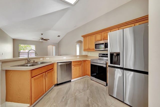 kitchen featuring lofted ceiling, sink, ceiling fan, kitchen peninsula, and stainless steel appliances