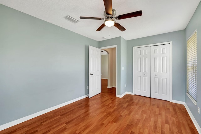 unfurnished bedroom featuring ceiling fan, a closet, light hardwood / wood-style flooring, and a textured ceiling