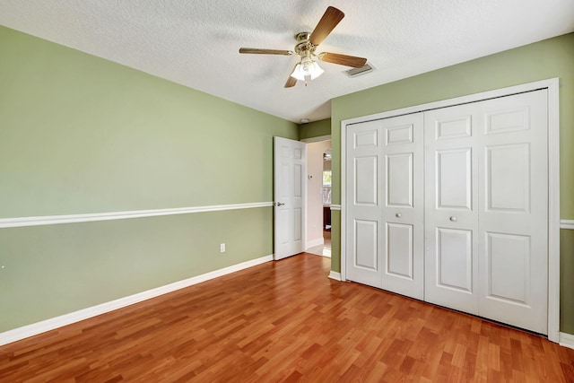 unfurnished bedroom featuring hardwood / wood-style flooring, ceiling fan, a textured ceiling, and a closet