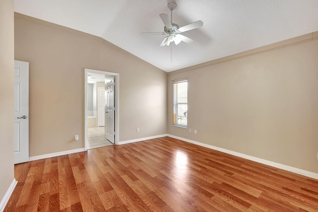 spare room with vaulted ceiling, ornamental molding, ceiling fan, and light wood-type flooring