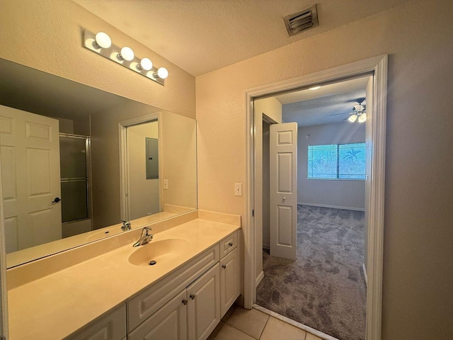 bathroom with tile patterned flooring, electric panel, vanity, a textured ceiling, and a shower with shower door