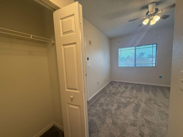 unfurnished bedroom with ceiling fan, a textured ceiling, and dark carpet