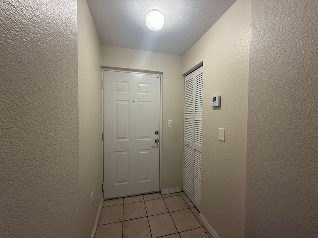 doorway to outside featuring a textured ceiling and light tile patterned flooring