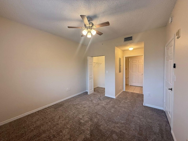 unfurnished bedroom with light carpet, a textured ceiling, electric panel, a closet, and ceiling fan