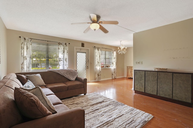 living room featuring ceiling fan with notable chandelier, a textured ceiling, and light wood-type flooring