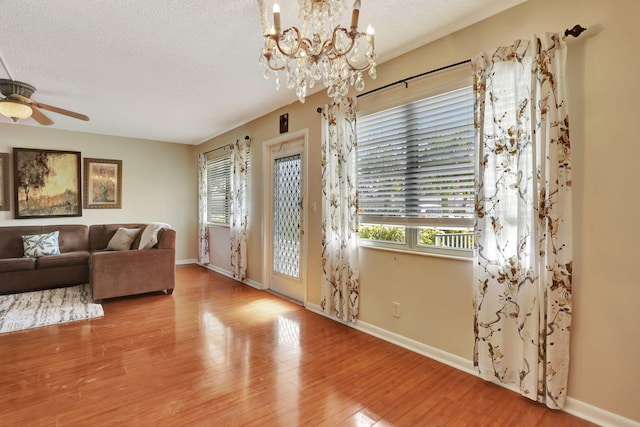 interior space with ceiling fan with notable chandelier, light hardwood / wood-style floors, and a textured ceiling