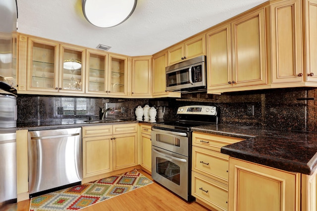 kitchen featuring tasteful backsplash, appliances with stainless steel finishes, sink, and light hardwood / wood-style flooring