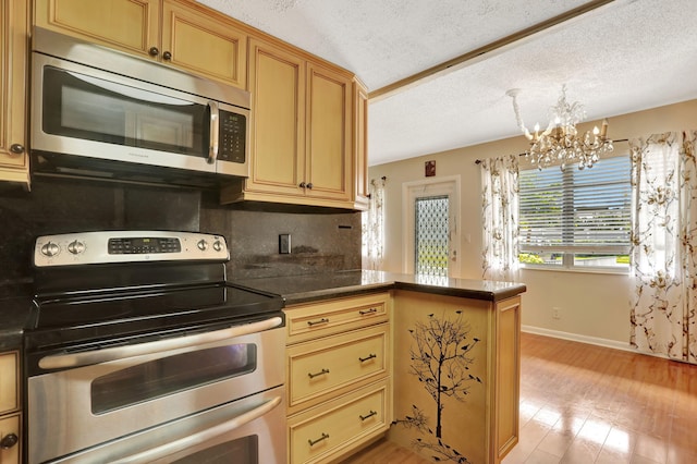 kitchen with appliances with stainless steel finishes, backsplash, kitchen peninsula, a chandelier, and light wood-type flooring