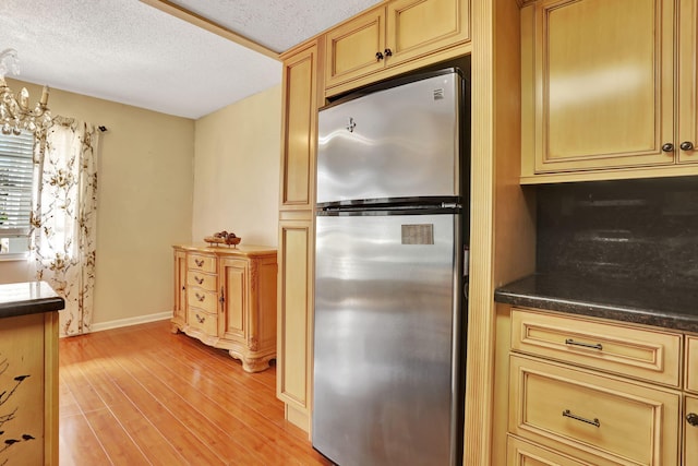 kitchen featuring stainless steel fridge, a textured ceiling, and light wood-type flooring