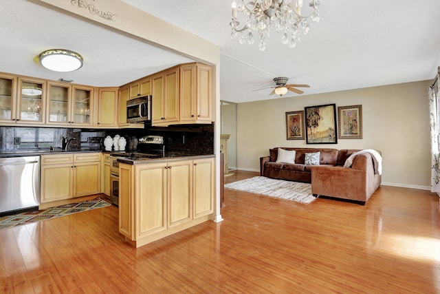 kitchen with light brown cabinetry, ceiling fan, stainless steel appliances, light hardwood / wood-style floors, and decorative backsplash