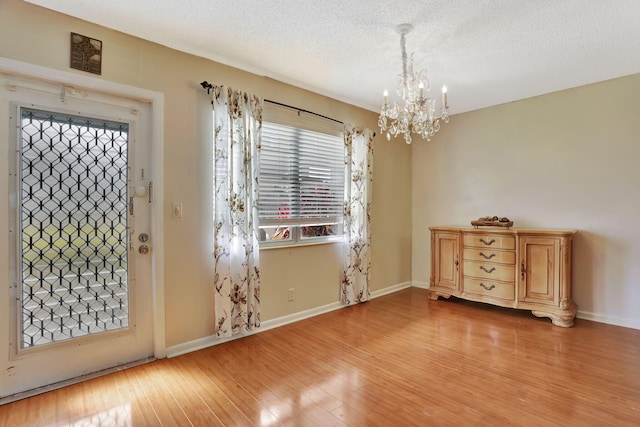 entryway featuring an inviting chandelier, a textured ceiling, and light wood-type flooring