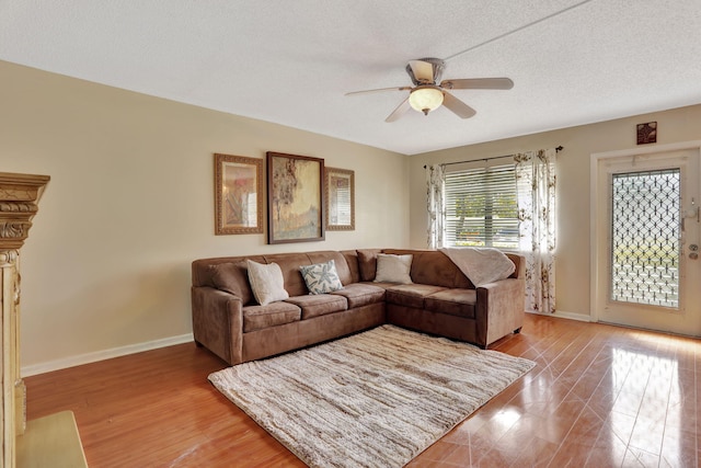 living room featuring ceiling fan, a textured ceiling, and light wood-type flooring