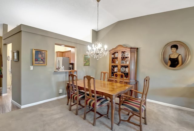 dining area with lofted ceiling, light colored carpet, and an inviting chandelier