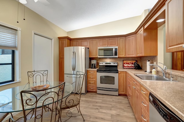 kitchen featuring lofted ceiling, sink, tasteful backsplash, light wood-type flooring, and appliances with stainless steel finishes