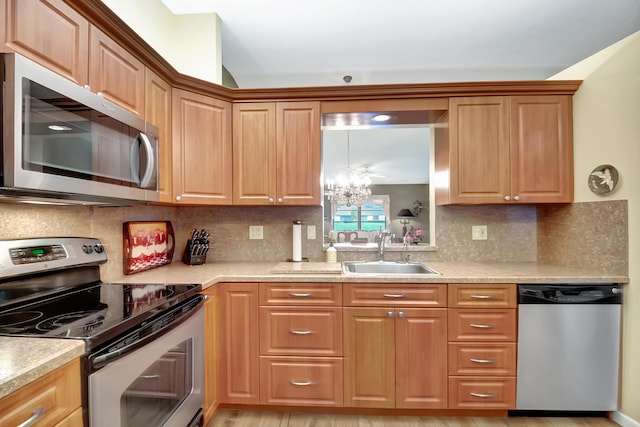 kitchen featuring an inviting chandelier, sink, backsplash, and stainless steel appliances