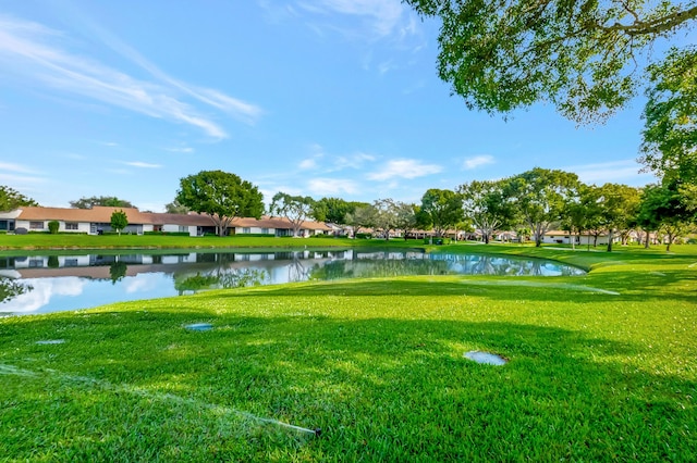 view of property's community with a lawn and a water view