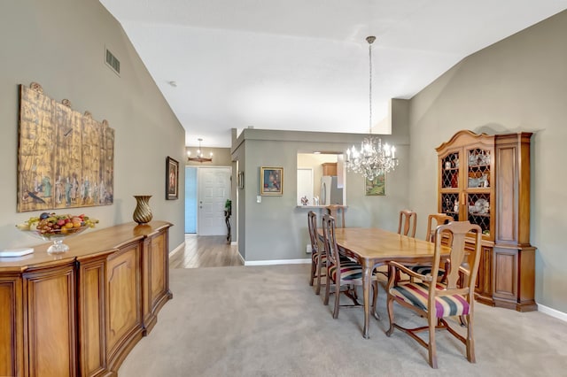 carpeted dining room with an inviting chandelier and high vaulted ceiling