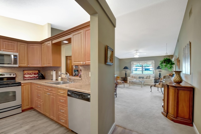 kitchen with sink, light colored carpet, appliances with stainless steel finishes, ceiling fan, and backsplash