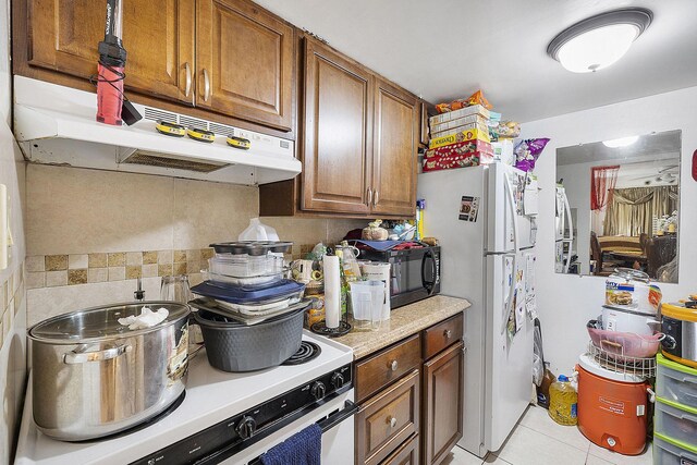 kitchen with tasteful backsplash, light tile patterned floors, and white appliances