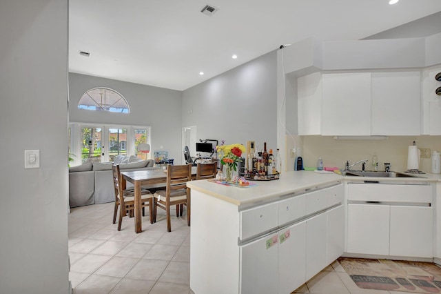 kitchen with sink, white cabinets, light tile patterned floors, kitchen peninsula, and french doors