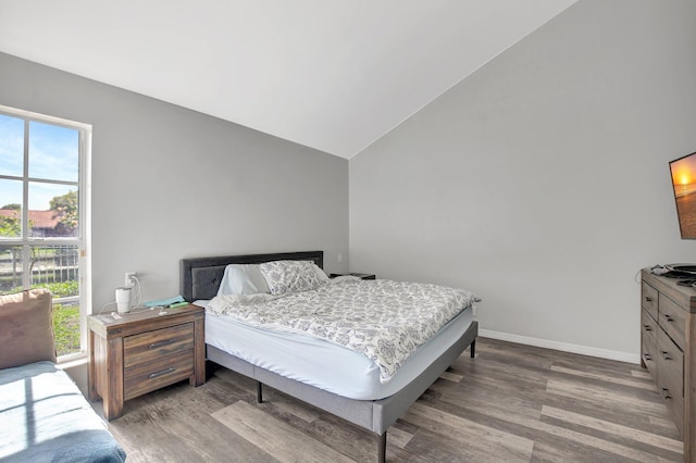 bedroom with wood-type flooring and vaulted ceiling