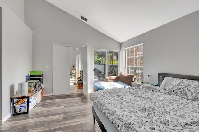 bedroom featuring hardwood / wood-style flooring, access to exterior, and high vaulted ceiling