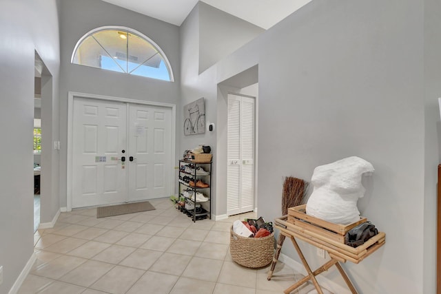 foyer entrance with light tile patterned floors and a towering ceiling