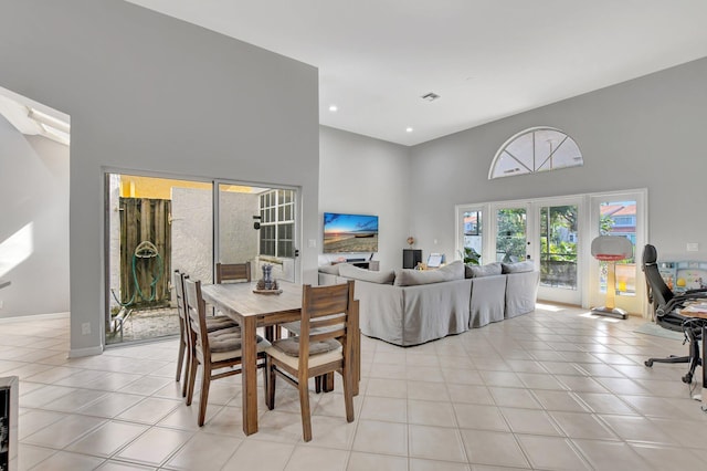 dining space featuring a towering ceiling, light tile patterned floors, and french doors