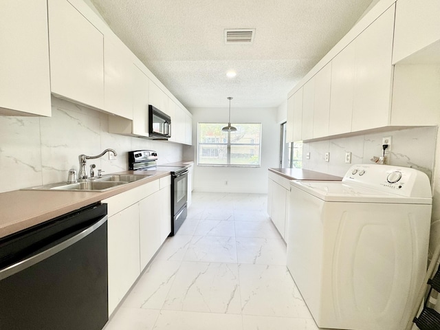 kitchen with washer / clothes dryer, black appliances, hanging light fixtures, and white cabinets