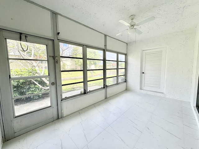 unfurnished sunroom featuring ceiling fan and a wealth of natural light