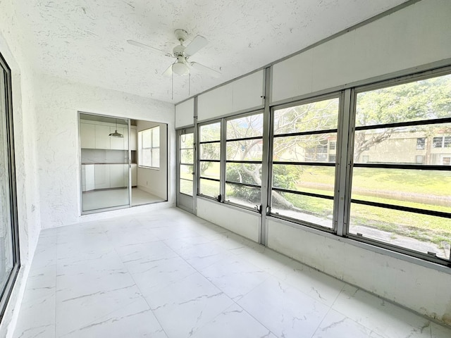 unfurnished sunroom featuring ceiling fan