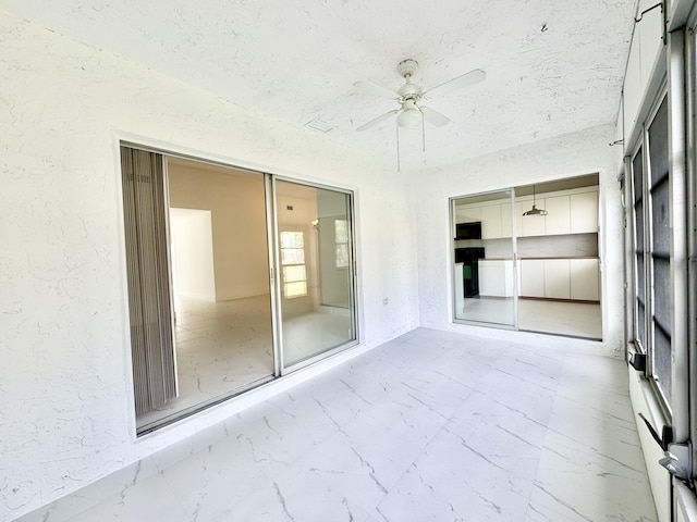 unfurnished sunroom featuring ceiling fan