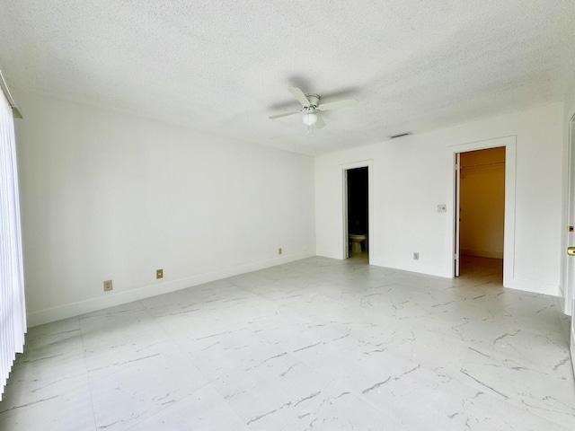 unfurnished room with ceiling fan and a textured ceiling