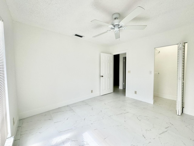 unfurnished bedroom featuring ceiling fan, a spacious closet, and a textured ceiling