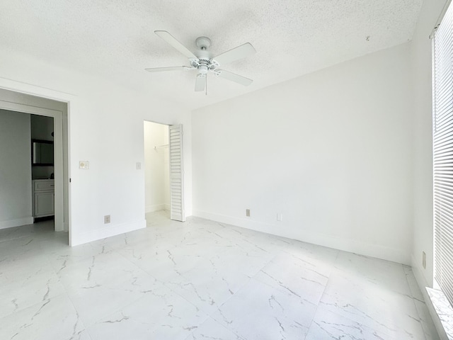 unfurnished bedroom featuring ceiling fan, a spacious closet, and a textured ceiling