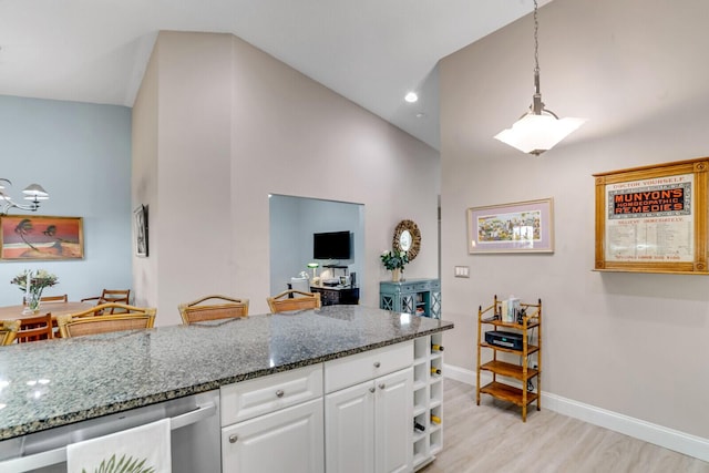 kitchen featuring decorative light fixtures, dark stone countertops, dishwasher, light hardwood / wood-style floors, and white cabinets