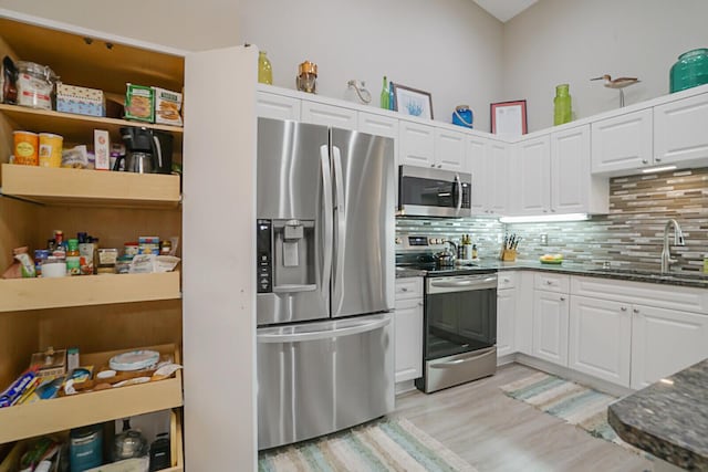 kitchen featuring sink, light wood-type flooring, appliances with stainless steel finishes, decorative backsplash, and white cabinets