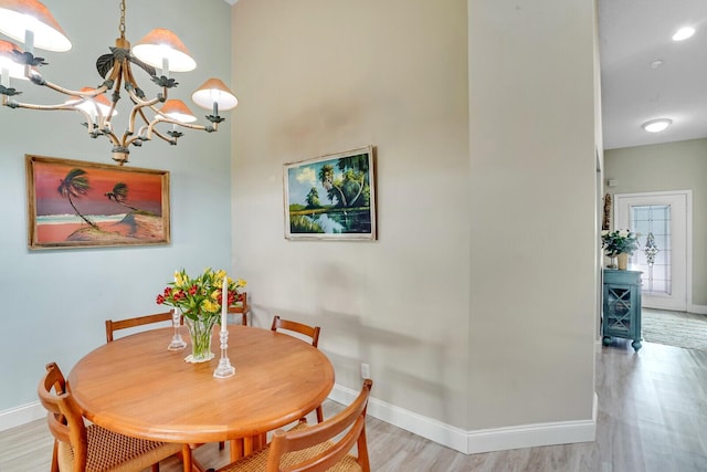 dining space featuring light wood-style floors, a chandelier, and baseboards