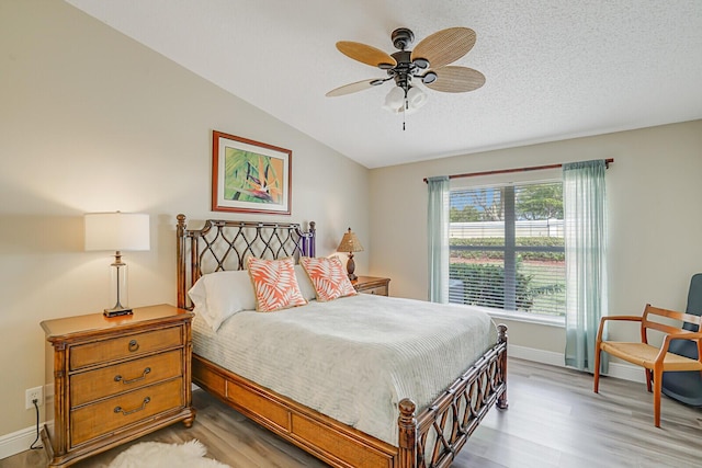 bedroom with lofted ceiling, a ceiling fan, a textured ceiling, wood finished floors, and baseboards