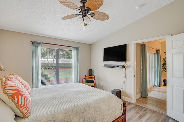 bedroom with lofted ceiling, a textured ceiling, a ceiling fan, baseboards, and light wood-style floors