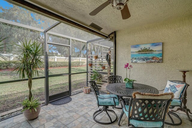 view of patio featuring ceiling fan, area for grilling, and a lanai