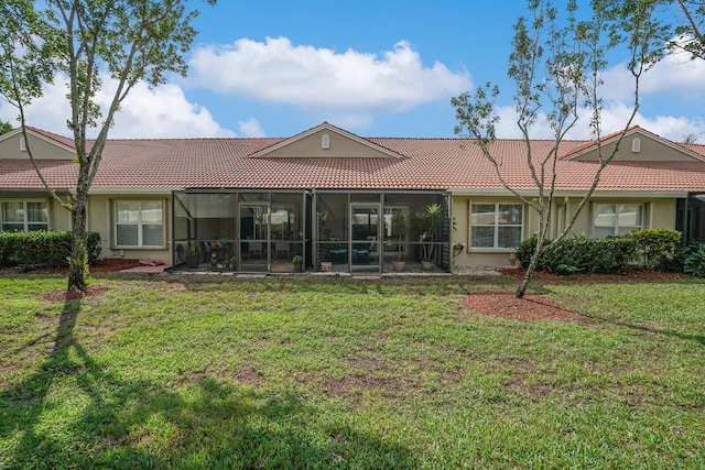 back of house featuring a yard, a tiled roof, a sunroom, and stucco siding