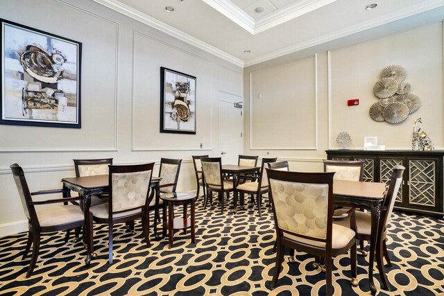 carpeted dining space with ornamental molding and a decorative wall